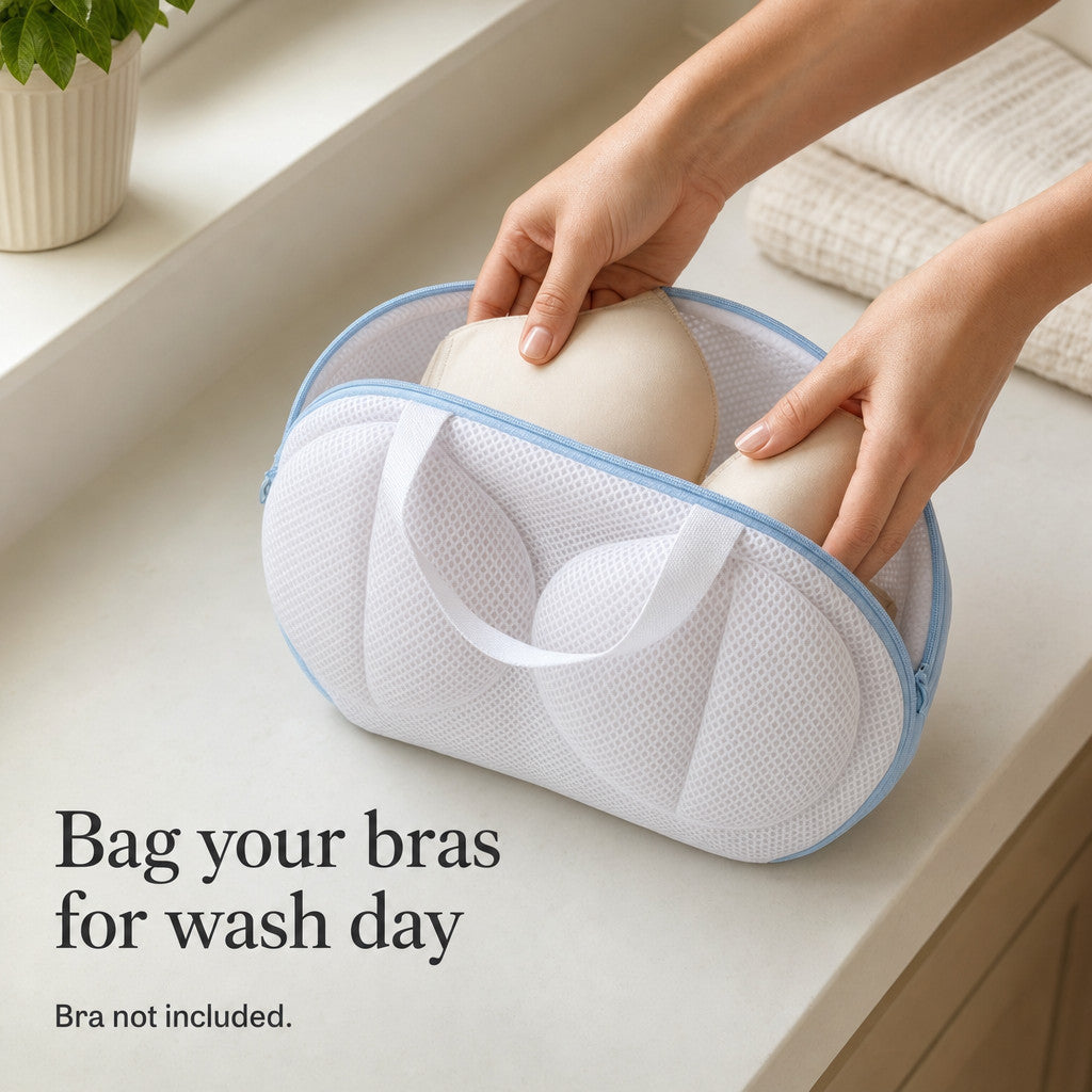 Hands placing a cream bra into the original white mesh bag with pale-blue zipper; bra is a demonstration prop and is not included.
