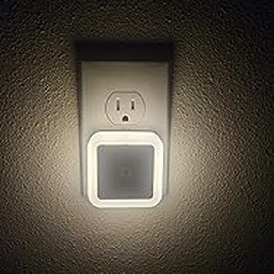 Warm white square night light glowing on a wall outlet