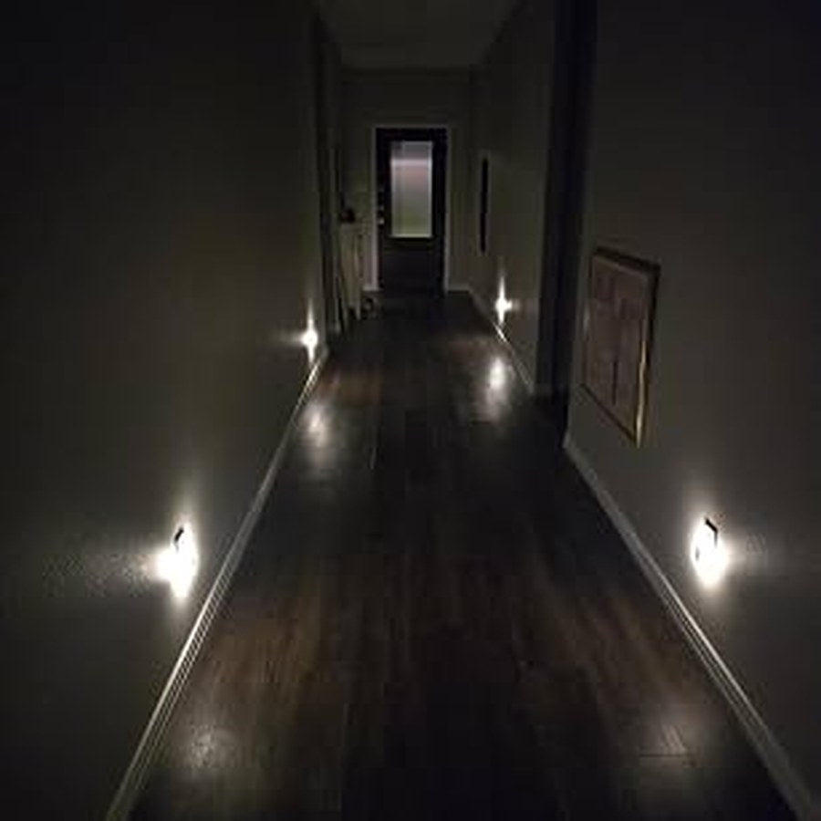 Warm white square night lights guiding a dark hallway