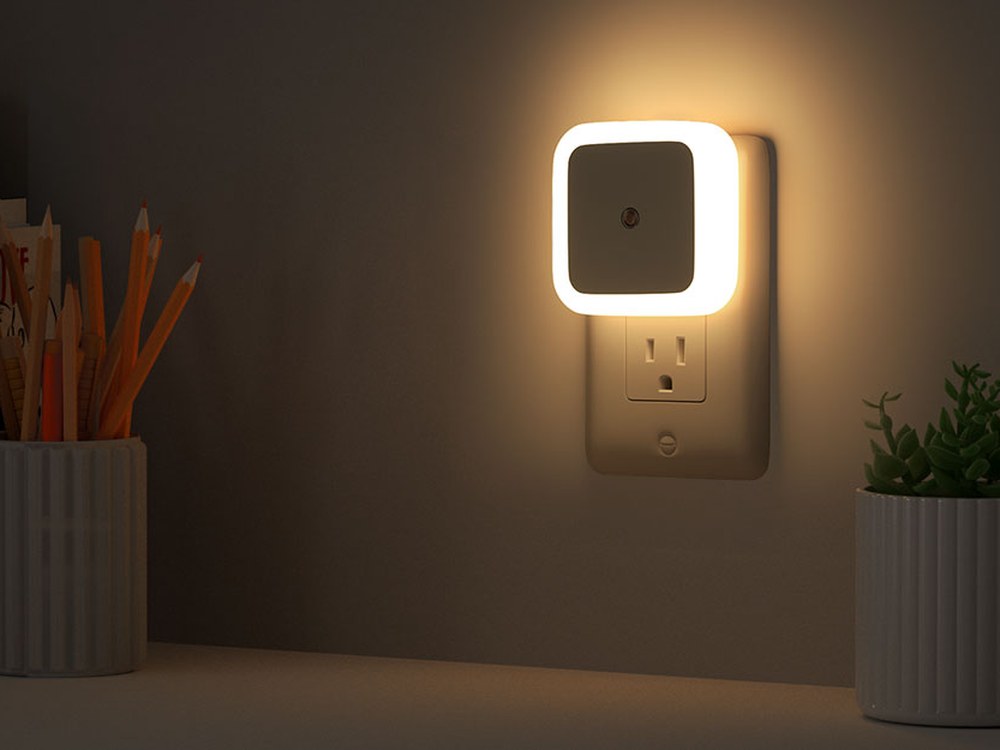 Warm white square night light on a wall outlet beside a shelf