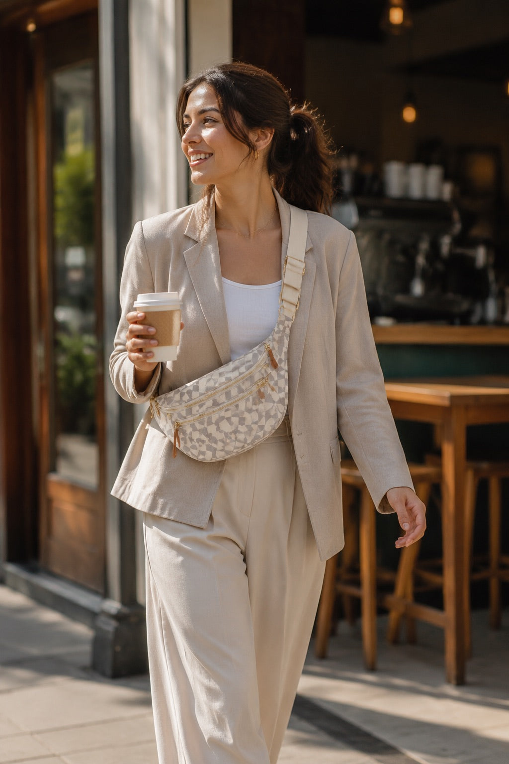 Woman styling the cream checkered sling bag on a city coffee run