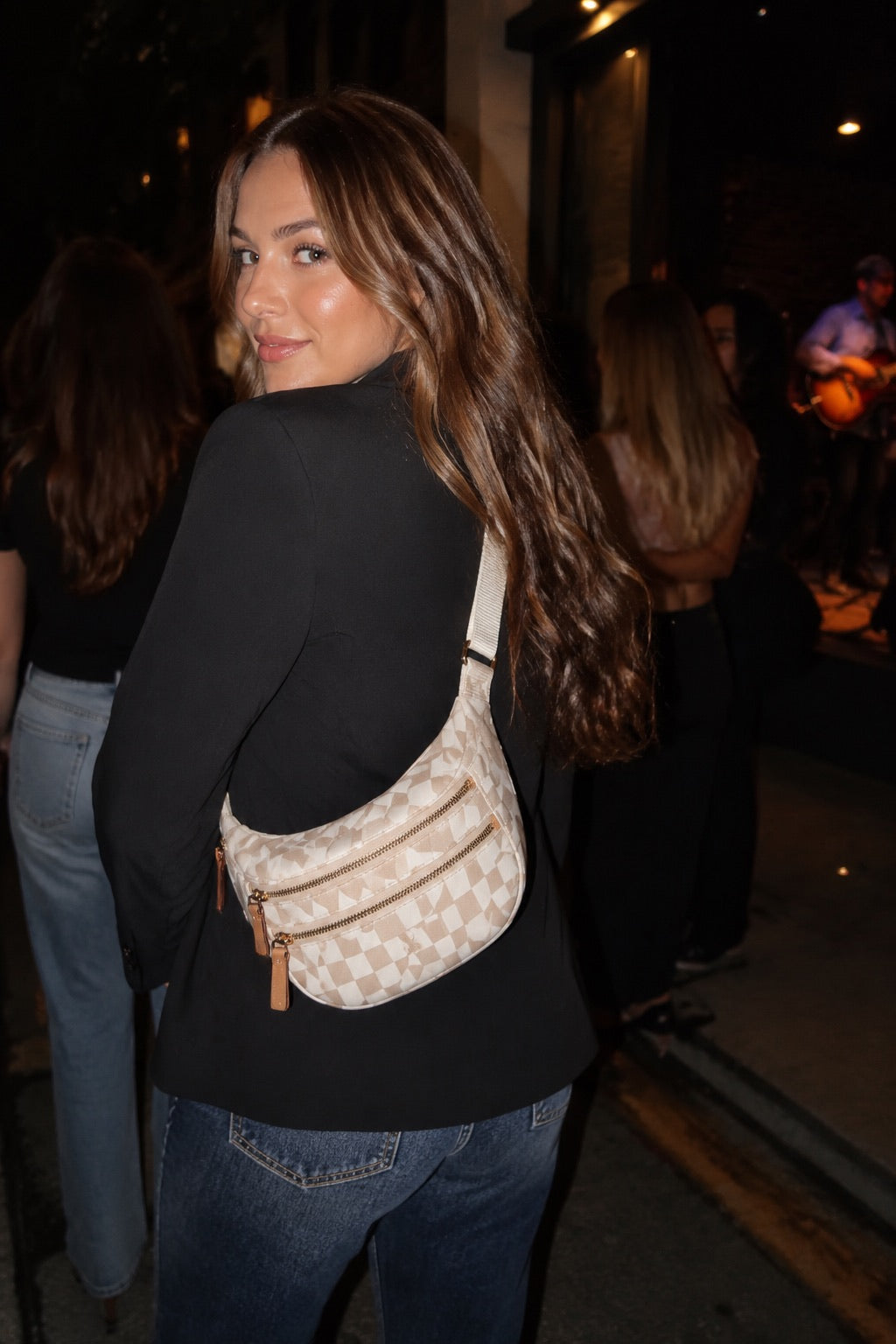 Woman wearing the cream checkered sling bag for an evening out